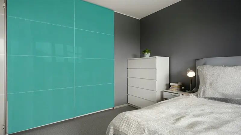 Sliding door wardrobe with deep teal fluted laminate sheet adding a stylish textured finish to a modern bedroom interior