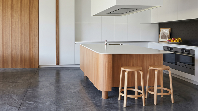 Modern kitchen featuring wood-grain post-forming laminate on a curved island countertop with smooth rounded edges and a sleek white surface.