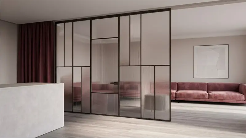 Modern living room featuring dark metal-framed glass wall panelling with clear and fluted panels acting as a room partition.